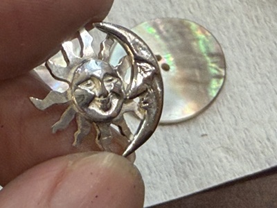 シェルの穴にシルバーのSun & Moonを差し込み、裏から固定しようとしている様子。
